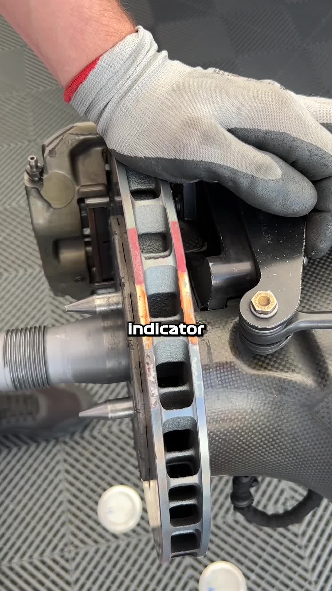 Gloved mechanic's hands inspecting a glowing race-car brake disc and caliper