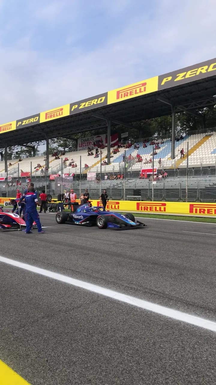 A PHM AIX Racing single-seater on the grid at Monza, Pirelli grandstand behind